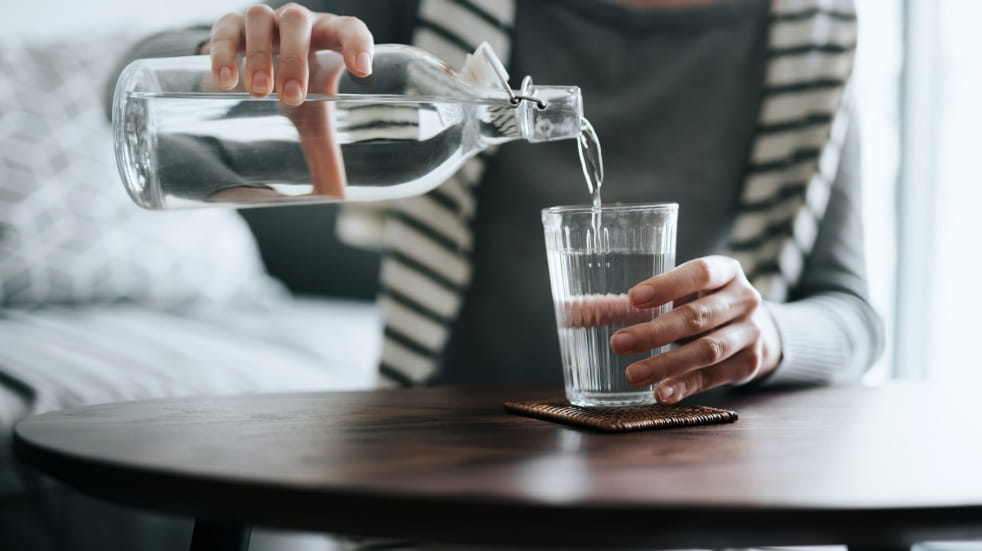 pouring water from glass bottle into glass